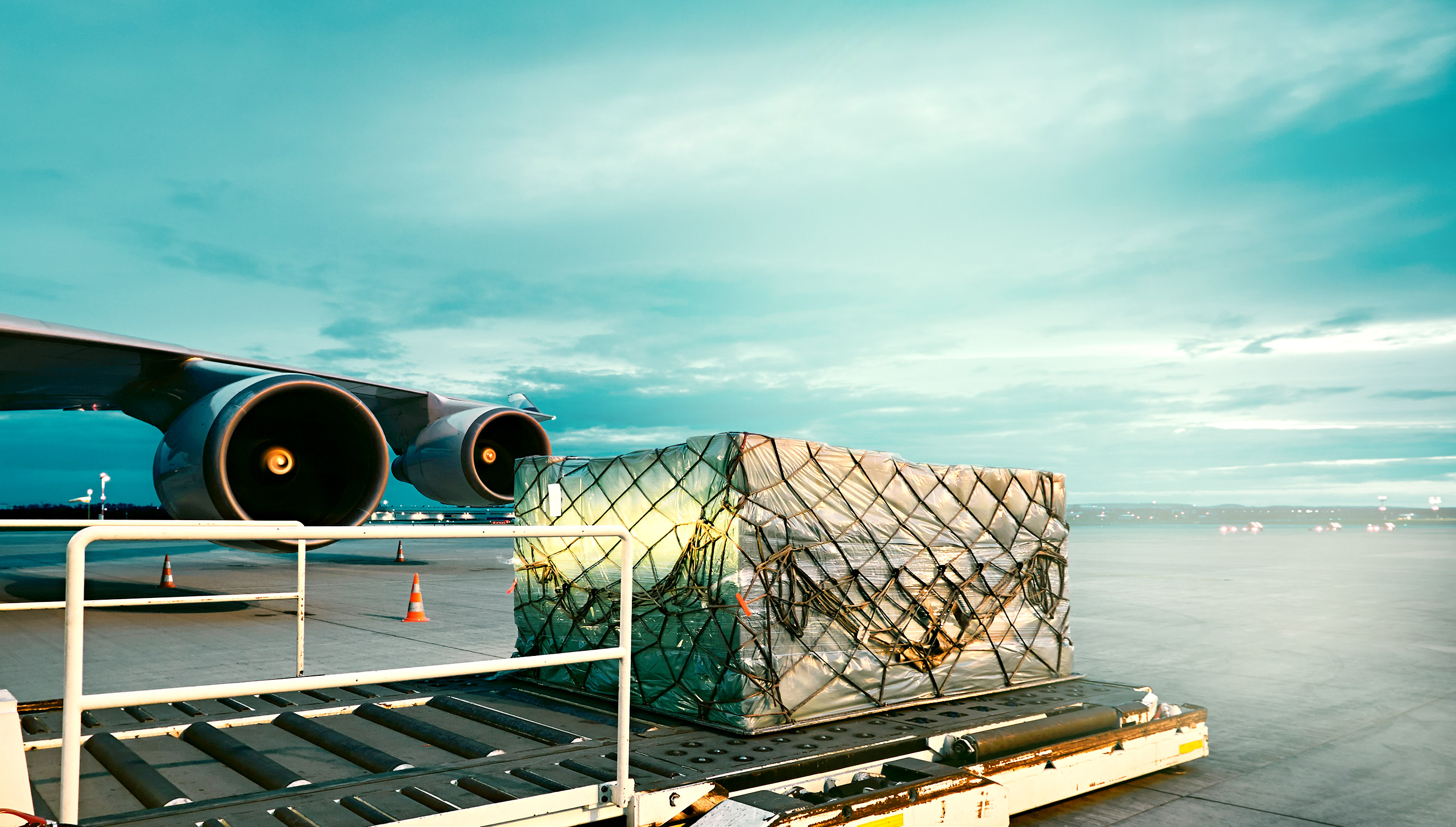 Freight on a conveyer belt outside at the airport being loaded onto or unloaded from a cargo plane